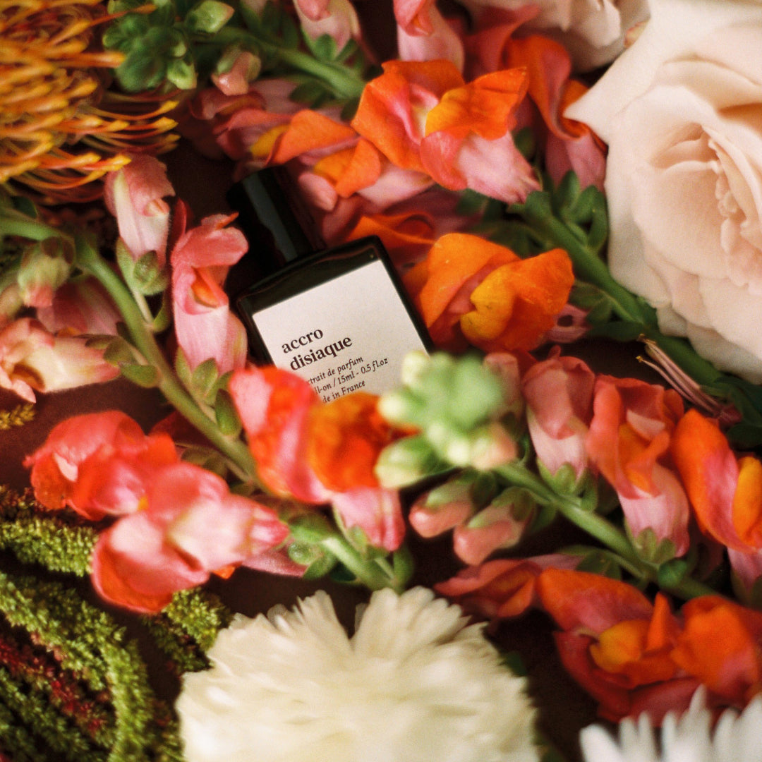 Flacon Accrodisiaque de Versatile Paris au milieu d'un bouquet de roses et de fleurs Immagine